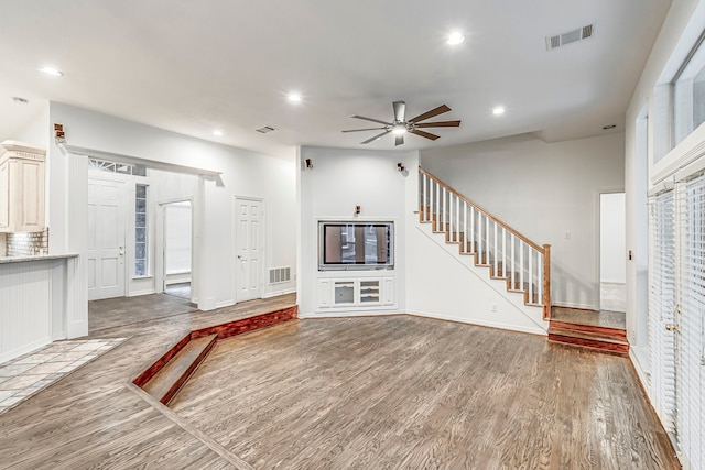 unfurnished living room with recessed lighting, wood finished floors, visible vents, and stairs