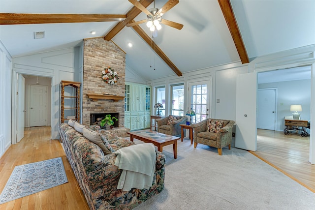 living room with a brick fireplace, beam ceiling, light hardwood / wood-style flooring, and high vaulted ceiling