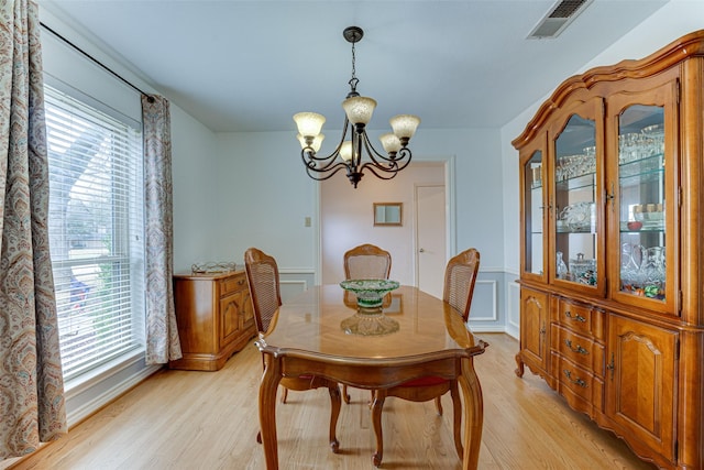 dining area with light hardwood / wood-style floors and a notable chandelier