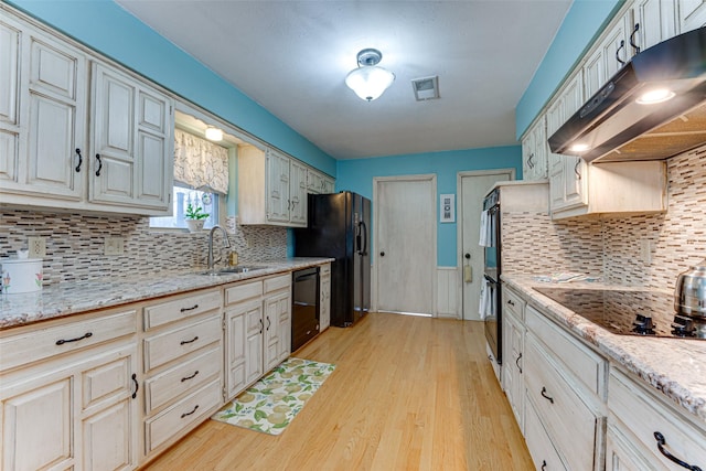 kitchen with light stone countertops, sink, cream cabinetry, and black appliances