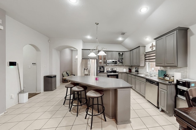 kitchen with sink, gray cabinetry, hanging light fixtures, stainless steel appliances, and a kitchen island