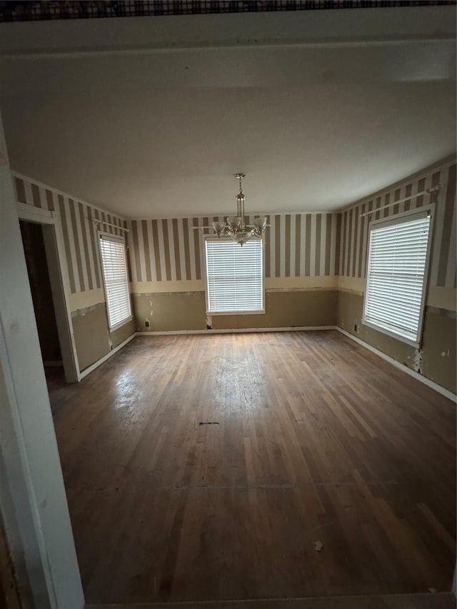 spare room featuring wood-type flooring and an inviting chandelier