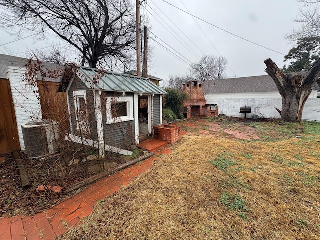 view of yard with central AC, an outdoor fireplace, and an outbuilding