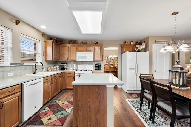 kitchen with sink, a chandelier, hanging light fixtures, a center island, and white appliances