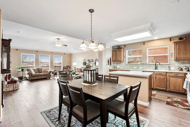 dining room featuring sink, ceiling fan with notable chandelier, and light wood-type flooring