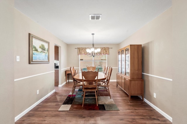 dining room with dark hardwood / wood-style flooring and an inviting chandelier