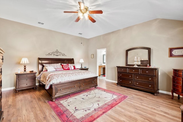 bedroom featuring ceiling fan, ensuite bathroom, vaulted ceiling, and light hardwood / wood-style flooring