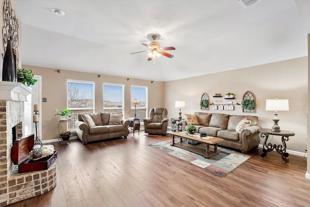 living room with a brick fireplace, hardwood / wood-style flooring, and ceiling fan