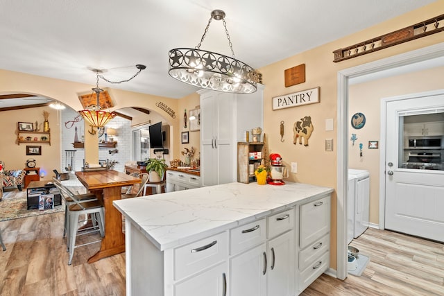 kitchen with white cabinetry, separate washer and dryer, hanging light fixtures, and light hardwood / wood-style flooring