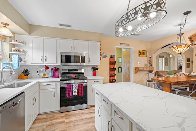 kitchen with stainless steel appliances, white cabinetry, sink, and pendant lighting