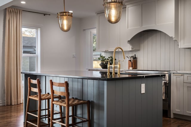 kitchen featuring a breakfast bar, decorative light fixtures, backsplash, dark hardwood / wood-style flooring, and kitchen peninsula