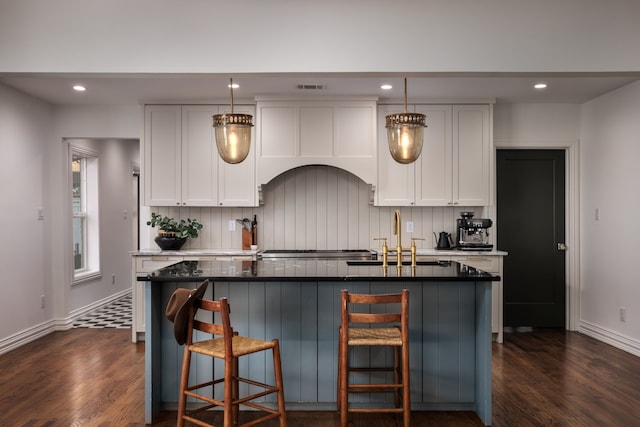 kitchen with premium range hood, sink, white cabinetry, dark hardwood / wood-style floors, and an island with sink