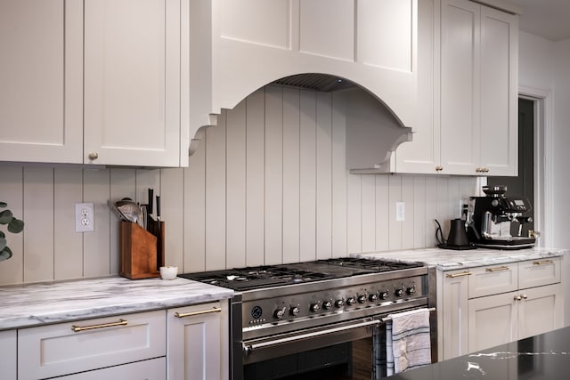 kitchen featuring stainless steel stove, light stone countertops, and white cabinets