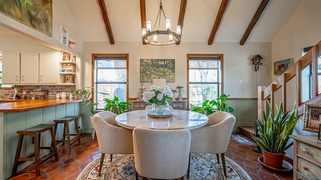 dining space with a healthy amount of sunlight, a chandelier, and vaulted ceiling with beams