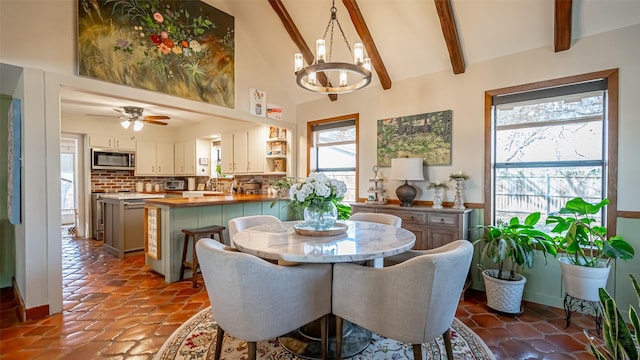 dining room featuring lofted ceiling with beams and ceiling fan with notable chandelier