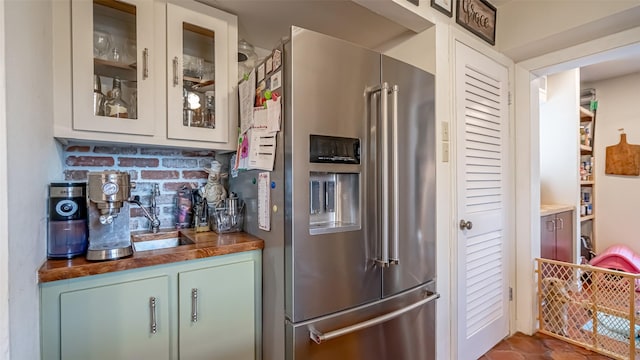 kitchen featuring wood counters, sink, and high quality fridge