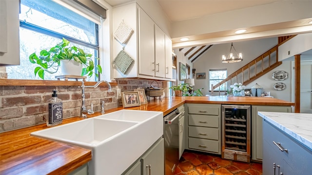 kitchen with sink, an inviting chandelier, wood counters, decorative light fixtures, and beverage cooler