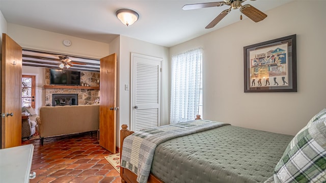 bedroom featuring ceiling fan, a fireplace, and a closet