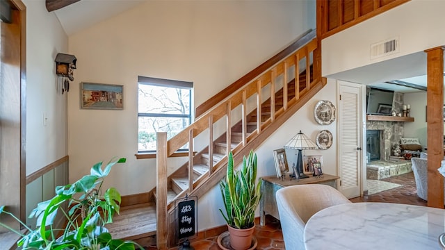 stairs featuring a fireplace and high vaulted ceiling