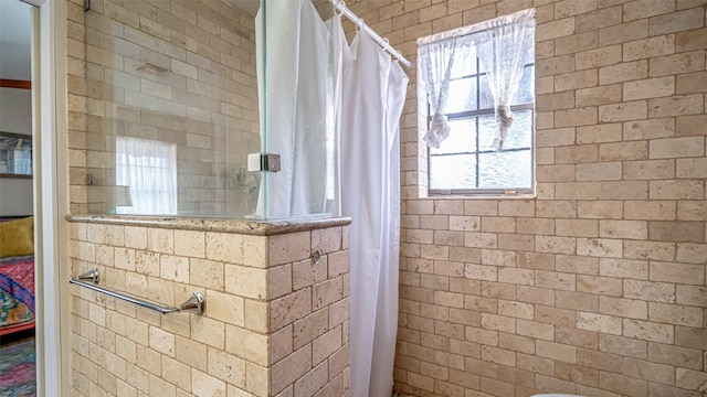 bathroom featuring curtained shower and brick wall