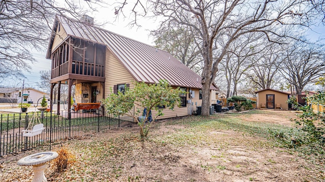 back of property with a shed and a sunroom