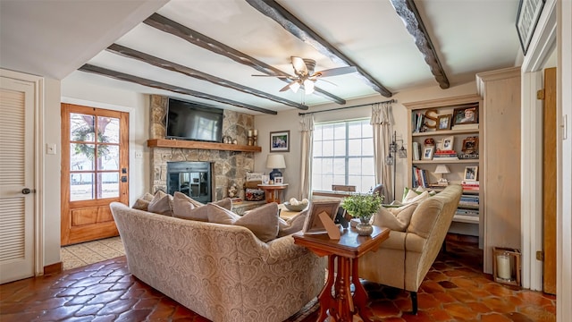 living room featuring ceiling fan, a fireplace, and beam ceiling