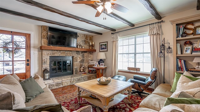 living room with beamed ceiling, ceiling fan, a fireplace, and a wealth of natural light