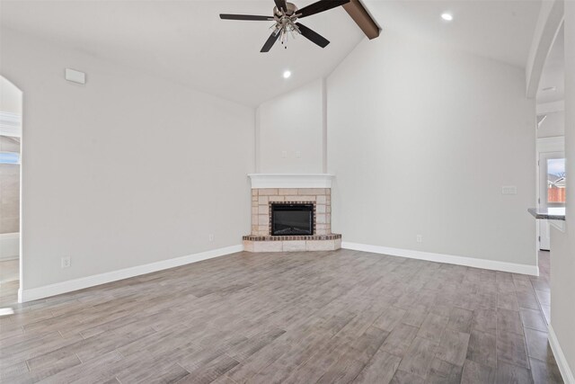 729 Jameson, Springtown, TX 76082 - unfurnished living room featuring beamed ceiling, a ceiling fan, wood finished floors, high vaulted ceiling, and a stone fireplace