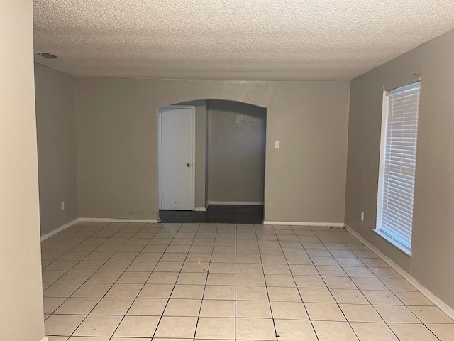 tiled spare room with a textured ceiling