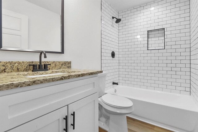 full bathroom with hardwood / wood-style flooring, vanity, toilet, and tiled shower / bath