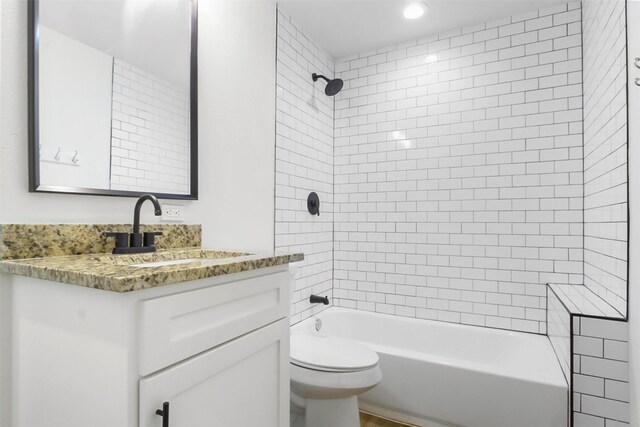 full bathroom with vanity, tiled shower / bath, and toilet