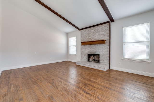 unfurnished living room featuring a brick fireplace, vaulted ceiling with beams, baseboards, and wood finished floors