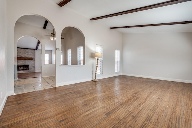 unfurnished living room featuring ceiling fan, light wood finished floors, plenty of natural light, and baseboards