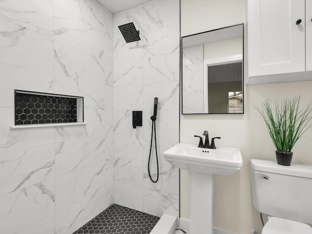 bathroom featuring sink, a tile shower, and toilet