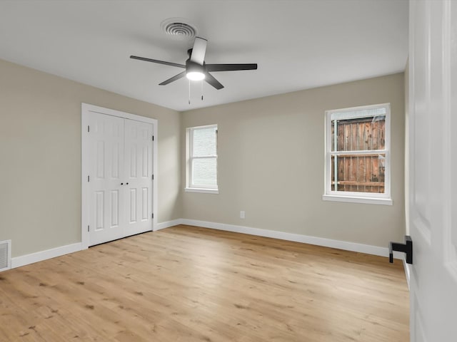 unfurnished bedroom with ceiling fan, light wood-type flooring, and a closet