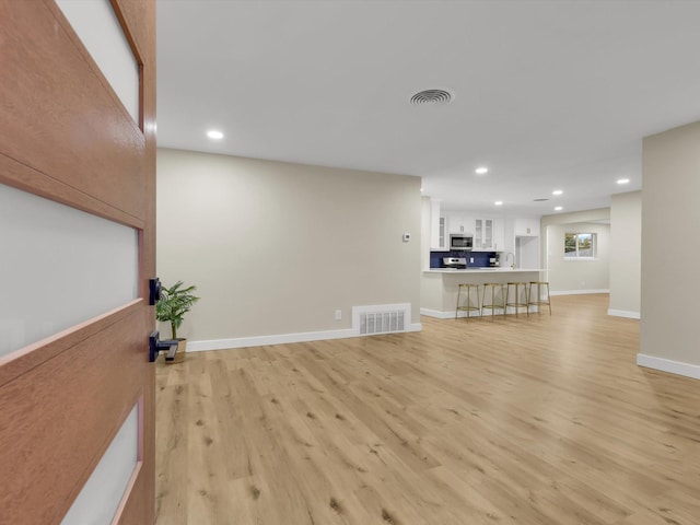 unfurnished living room featuring sink and light hardwood / wood-style flooring