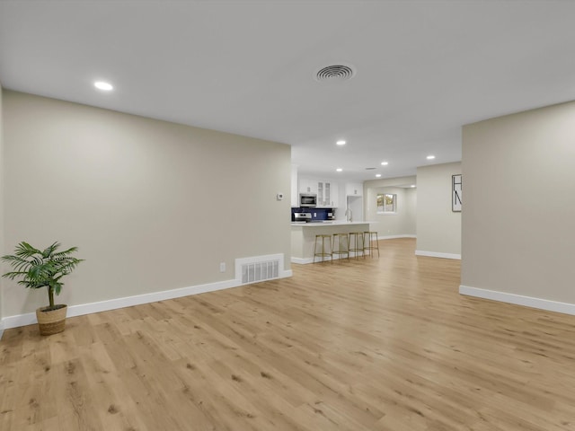 6005 Saint Johns Ln, Fort Worth, TX 76114 - kitchen featuring a peninsula, light wood finished floors, stainless steel appliances, a breakfast bar area, and backsplash