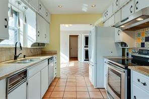 kitchen featuring tasteful backsplash, white cabinetry, sink, light tile patterned floors, and stainless steel appliances