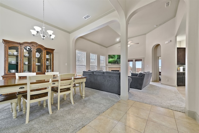 dining area featuring ceiling fan with notable chandelier, light tile patterned flooring, ornamental molding, and a towering ceiling