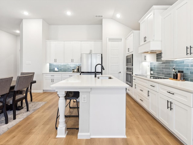 kitchen featuring sink, white cabinets, stainless steel appliances, a center island with sink, and light hardwood / wood-style flooring