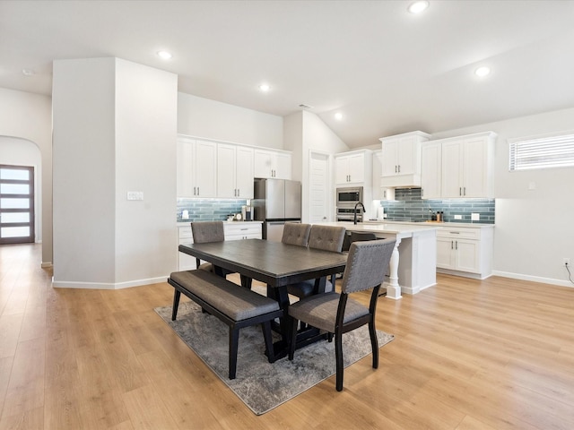 dining area featuring sink, vaulted ceiling, and light hardwood / wood-style floors