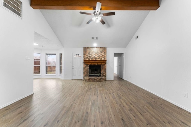 unfurnished living room with hardwood / wood-style flooring, ceiling fan, high vaulted ceiling, a brick fireplace, and beamed ceiling