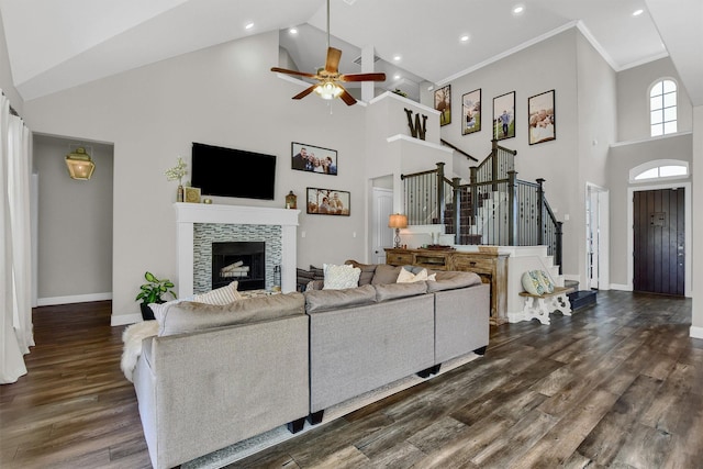 living room featuring high vaulted ceiling, a fireplace, ornamental molding, ceiling fan, and dark wood-type flooring