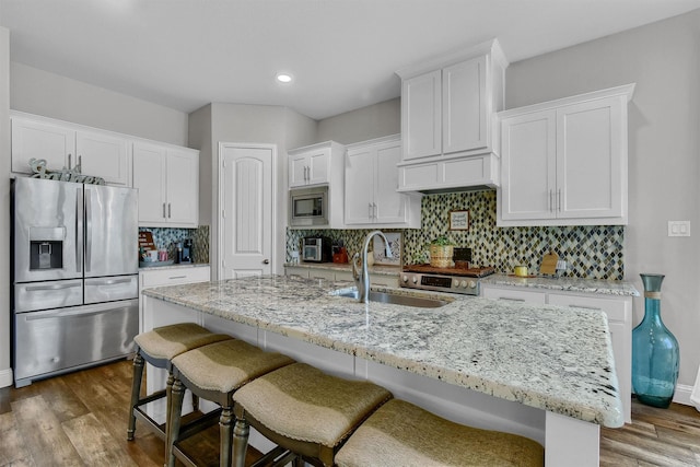 kitchen featuring dark wood-type flooring, sink, white cabinetry, a center island with sink, and stainless steel appliances