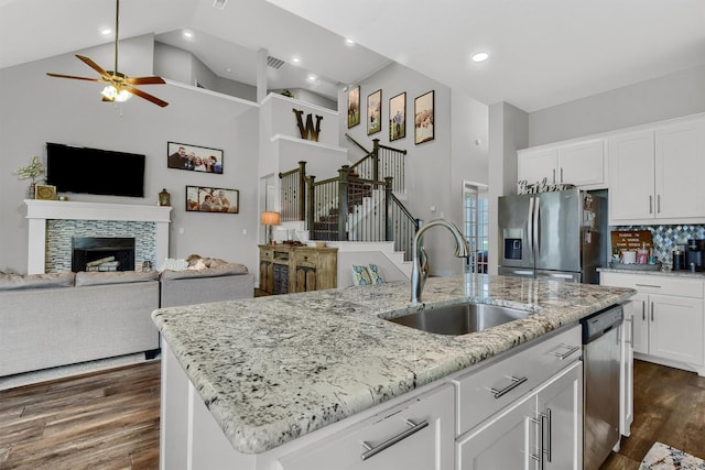 kitchen with sink, white cabinets, a kitchen island with sink, stainless steel appliances, and light stone countertops