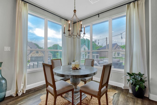 dining room with a healthy amount of sunlight, dark hardwood / wood-style flooring, and a chandelier