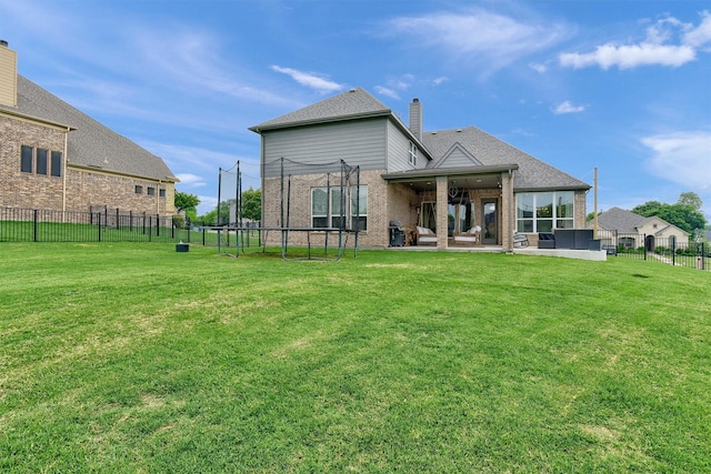 rear view of property with a yard, a patio area, and a trampoline