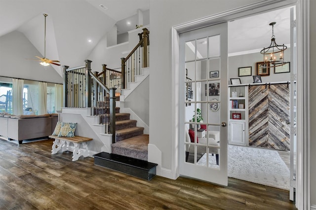 stairway with wood-type flooring, ceiling fan with notable chandelier, and high vaulted ceiling