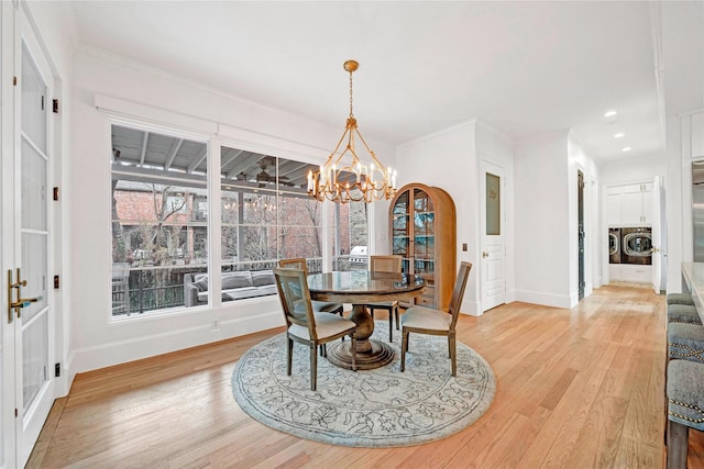 dining area with light wood-type flooring, ornamental molding, independent washer and dryer, and a notable chandelier