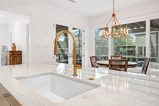 dining space with crown molding, pendant lighting, sink, and light stone countertops